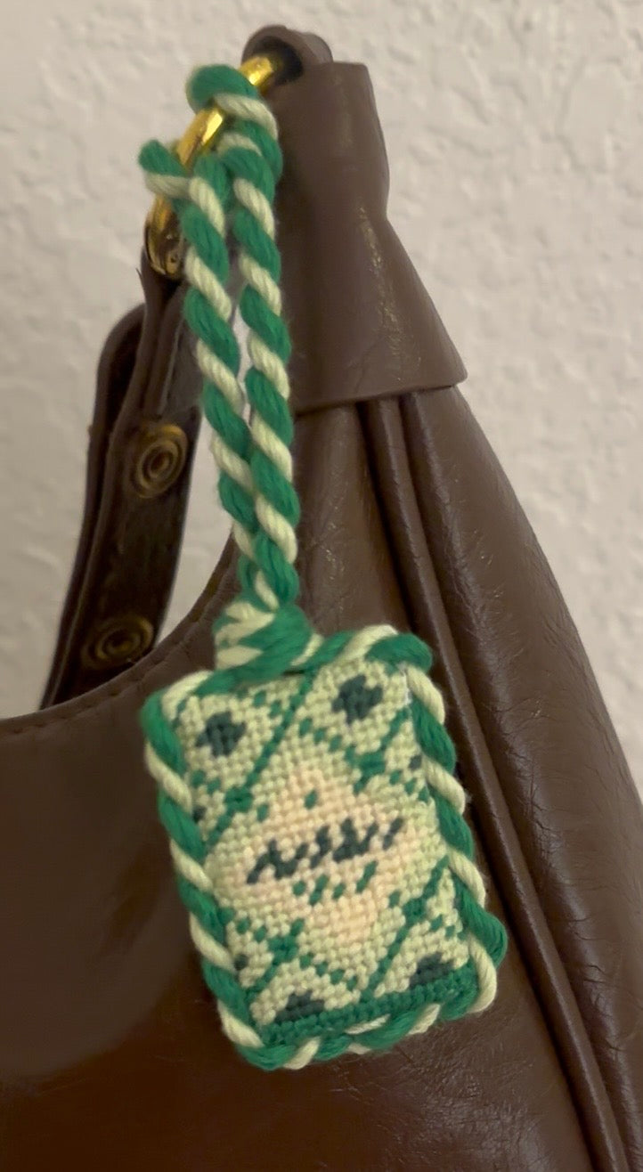 The green sea salt box pattern is now stitched and finished as a bag charm and is attached to a brown purse. 