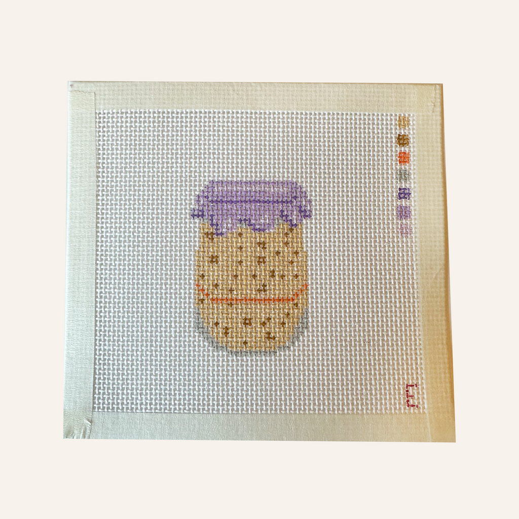 A needlepoint canvas featuring a sourdough starter pattern. The pattern showcases a jar filled with tan sourdough starter, an orange rubber band and purple lid cover. The canvas features a color palette panel and is signed by "Eloise."